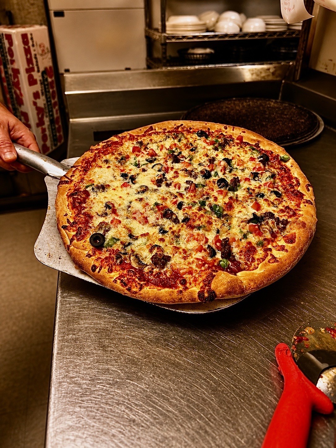 Fresh Porky's Pizza on a pizza peel in the kitchen
