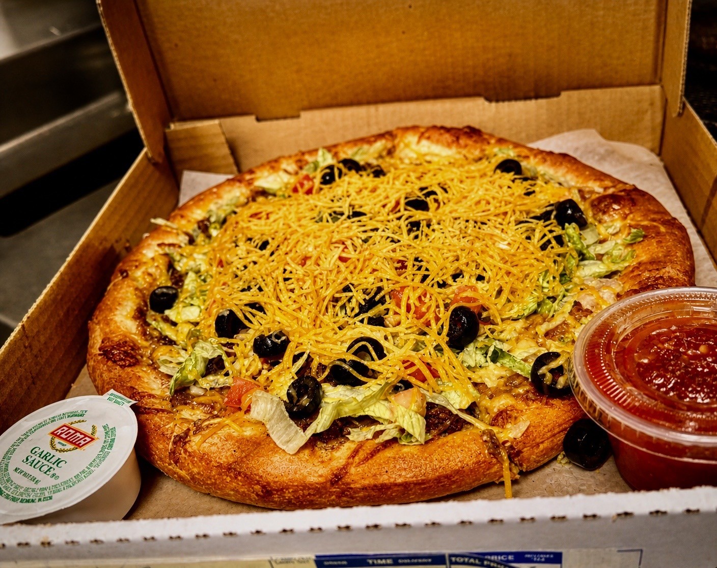 Taco specialty pizza in a box with sauces